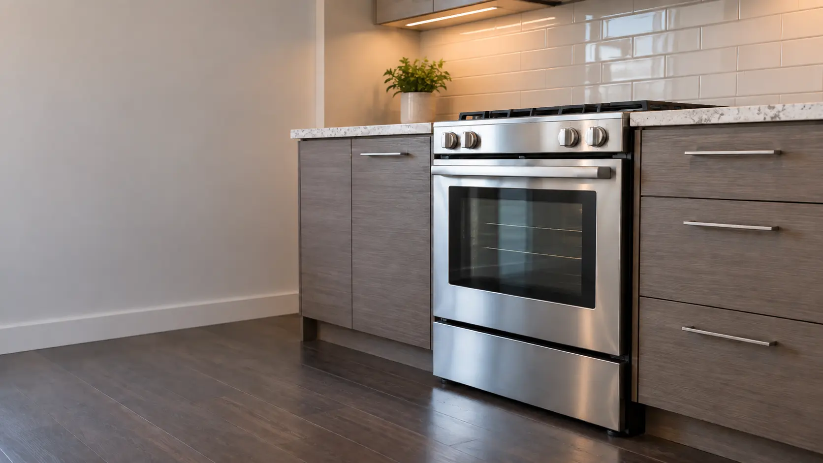 A kitchen with the range in a doorman-building apartment kitchen with a 24-inch range, seen from a low angle, the oven door glass catching the light.