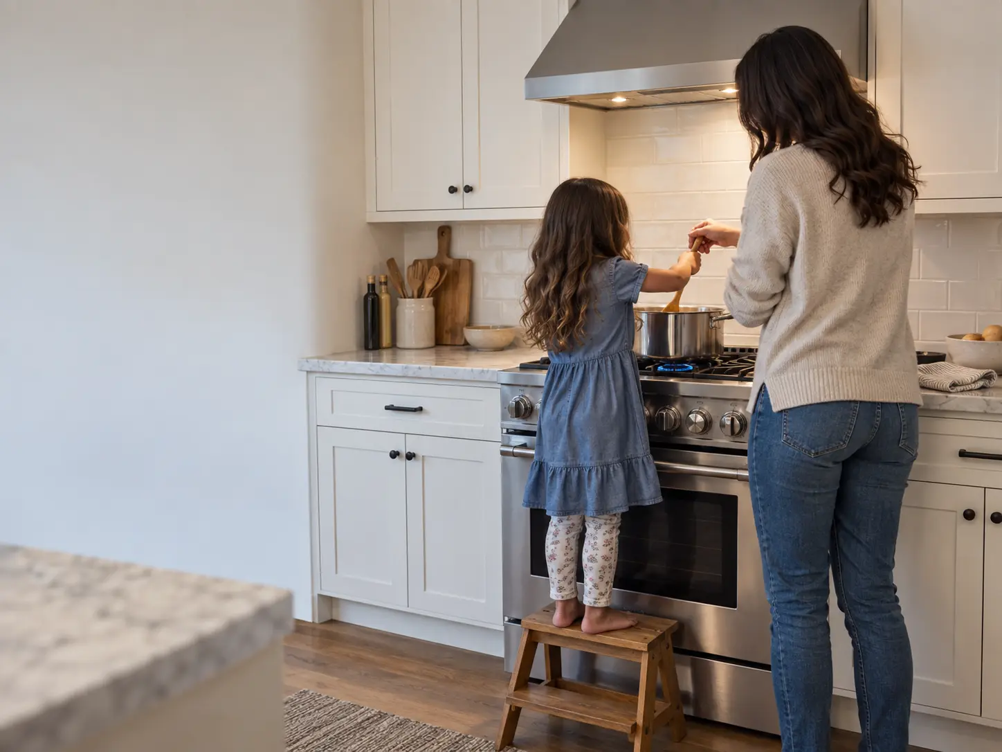 A parent and a child stirring a pot on a gas range together in a bright kitchen