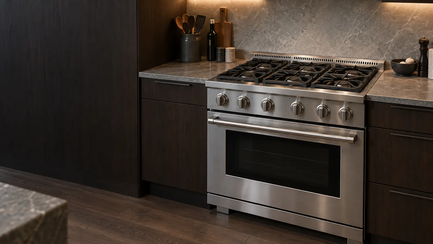 A 36-inch pro-style dual-fuel range in brushed stainless with six sealed burners under heavy cast-iron grates and large metal knobs, set between dark wood cabinets in a US home kitchen, every burner off and the oven door closed.